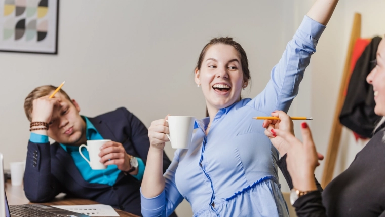 Employés de bureau assis autour d’une table en train de sourire et discuter.